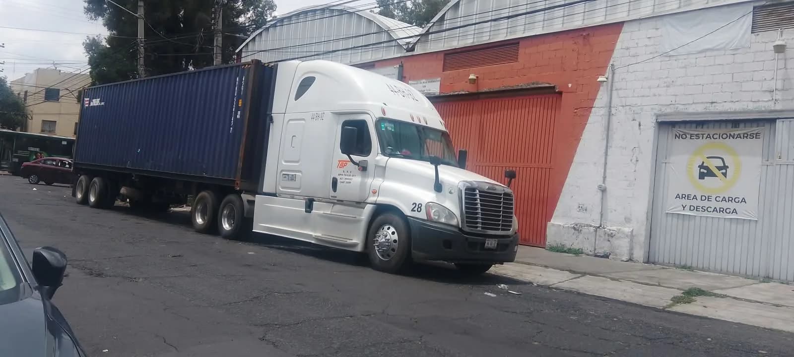 Tractocamión TBP con contenedor en una calle industrial
