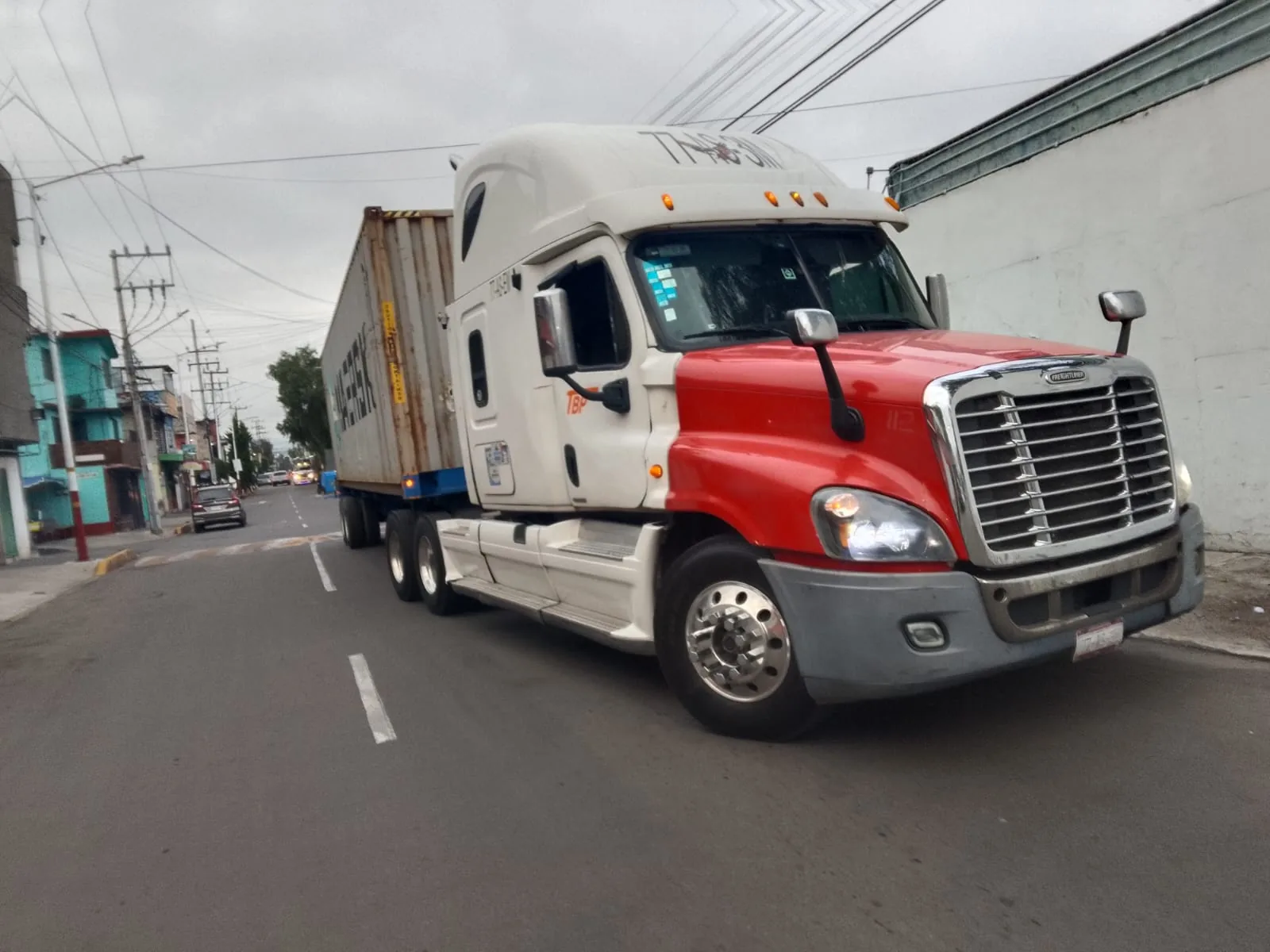 Tractocamión rojo y blanco de Transportes TBP en ruta